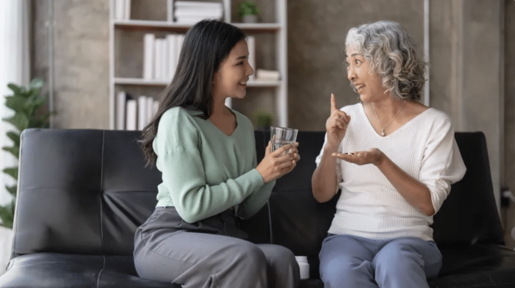 Una mujer joven conversa con una mujer mayor de 40 años sobre salud, bienestar y suplementos nutricionales en el salón de casa