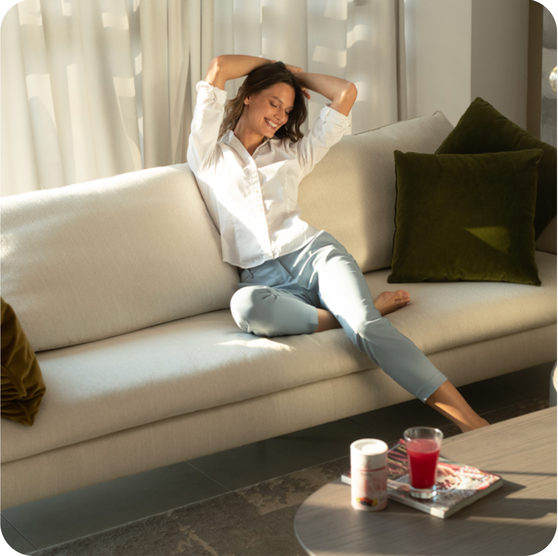 mujer sentada en el sofá de casa, aplicando el tratamiento de belleza fitline